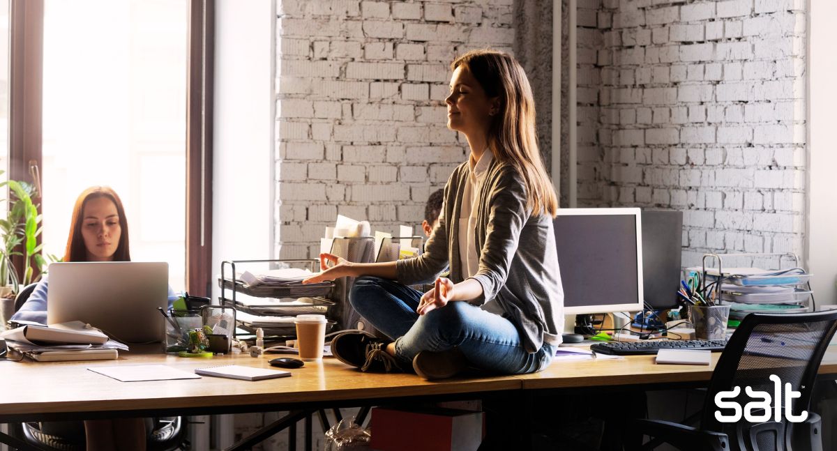 One way to manage stress at work is to take a break and meditate - this woman sits on her office desk!